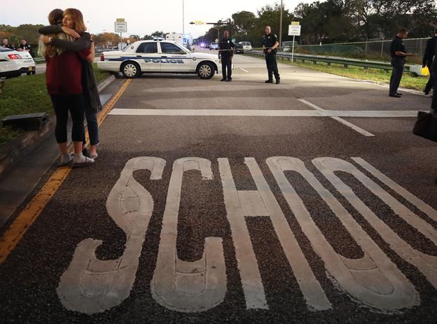 Kristi Gilroy (R), hugs a young woman at a police check point near the Marjory Stoneman Douglas High School where 17 people were killed by a gunman yesterday, on February 15, 2018 in Parkland, Florida. Police arrested the suspect after a short manhunt, and have identified him as 19-year-old former student Nikolas Cruz.